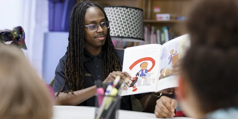 A man reads a book to a group of children