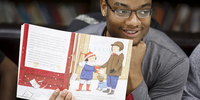 A man reads a book to a group of children