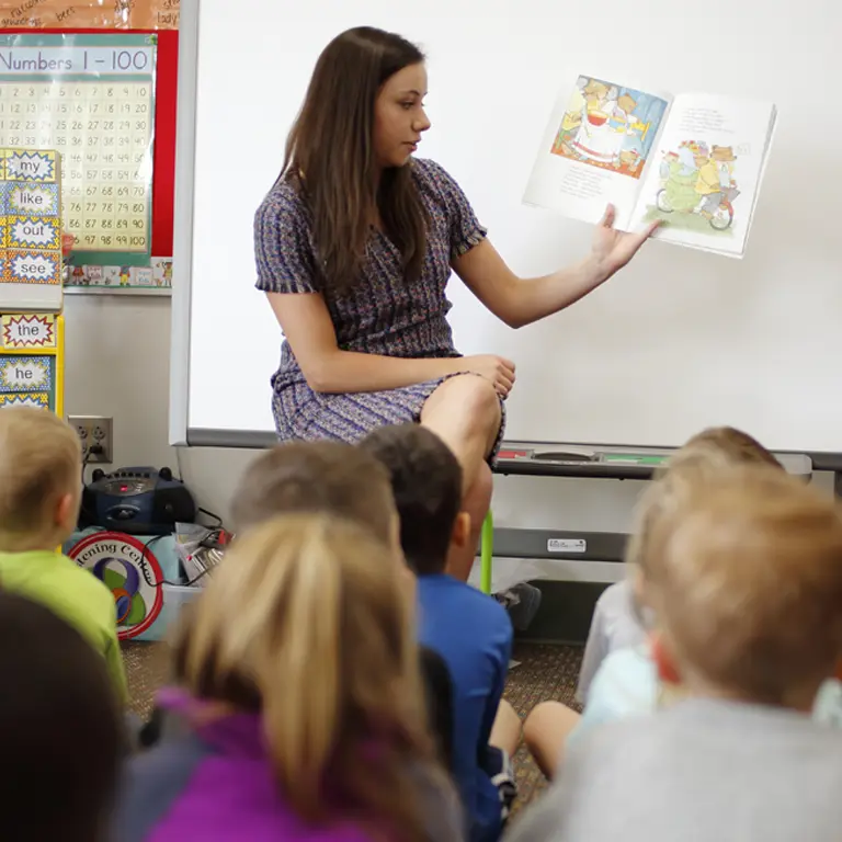 A female teacher reads to a classroom of children