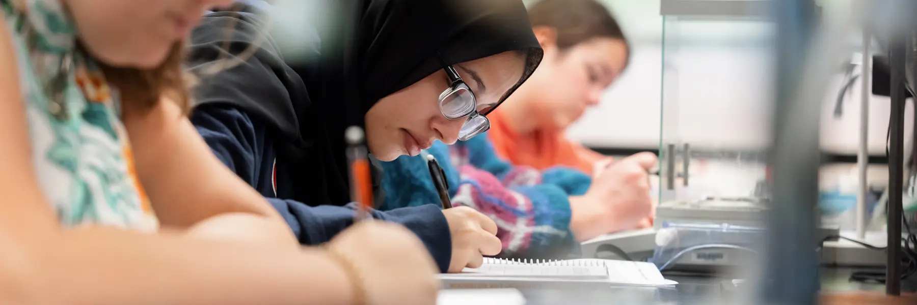 A female student in a black hijab takes a chemistry test