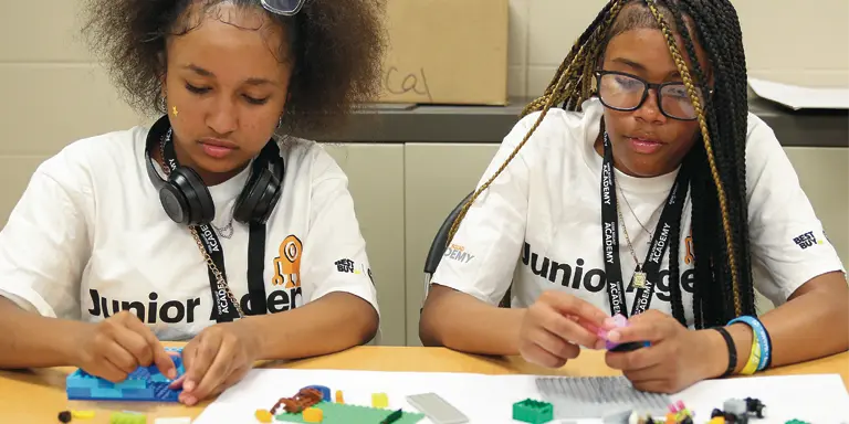 Two female participants of Kids College build with Legos