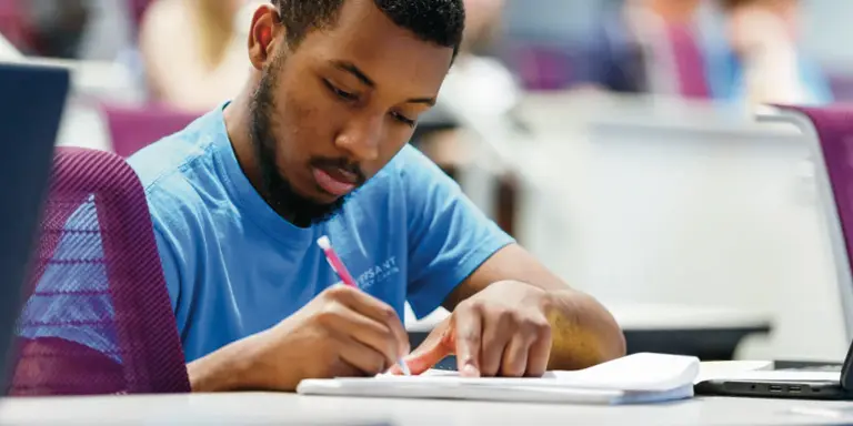 A male student takes an exam in a classroom